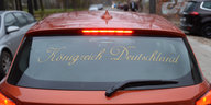 ein rotes Auto auf dessen Heckscheibe „Königreich Deutschland“ steht