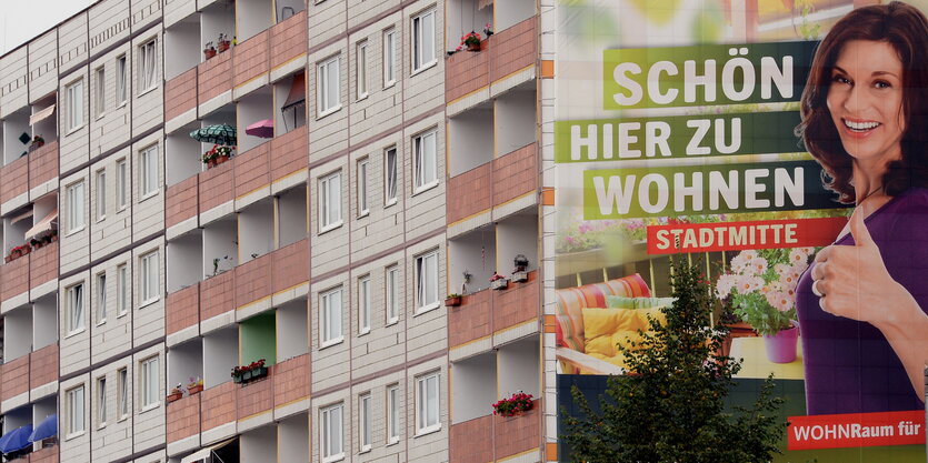 ein Plattenbau auf dessen Seite ein großes Plakat auf dem steht „Schön hier zu wohnen“