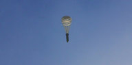 Eine Bombe, die an einem Fallschirm hängt, fällt durch den blauen Himmel