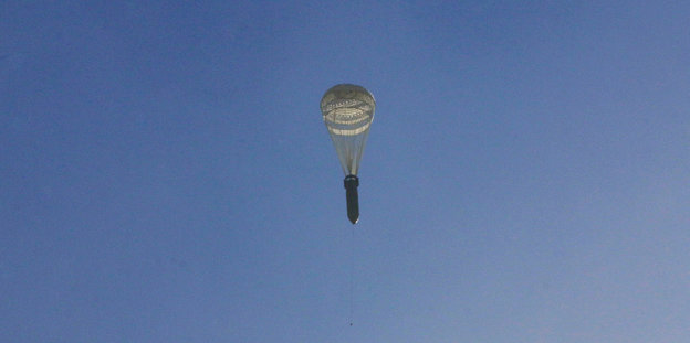Eine Bombe, die an einem Fallschirm hängt, fällt durch den blauen Himmel