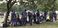 Soldaten in blauem Flecktarn machen eine Pause unter Bäumen