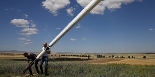 Zwei Männer bauen eine Windturbine auf