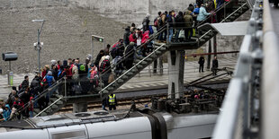 Auf einer Treppe, die von einem Zug wegführt, stauen sich Menschen