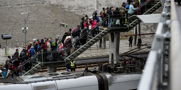 Auf einer Treppe, die von einem Zug wegführt, stauen sich Menschen