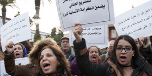 Rufende Menschen halten Schilder hoch, mit denen sie gegen Gewalt gegen Frauen protestieren