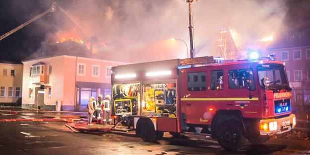 Ein Feuerwehrfahrzeug steht in Bautzen vor einer brennenden geplanten Flüchtlingsunterkunft.