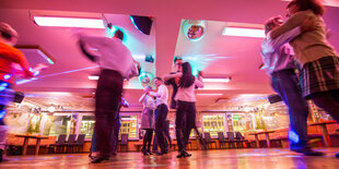 Im Saal einer Tanzschule tanzen mehrere Paare Standardtanz