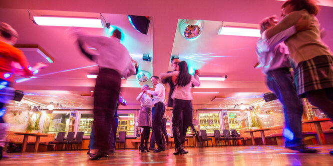 Im Saal einer Tanzschule tanzen mehrere Paare Standardtanz