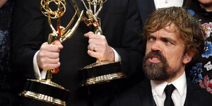 US-Schauspieler Peter Dinklage guckt ehrfürchtig auf zwei Awards
