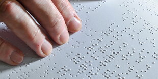 Eine Hand liest eine Seite in Brailleschrift