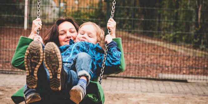 Eine Mutter schaukelt mit ihrem Sohn