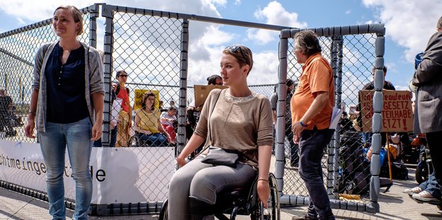 Eine Frau fährt mit ihrem Rollstuhl aus einem geöffneten Käfig