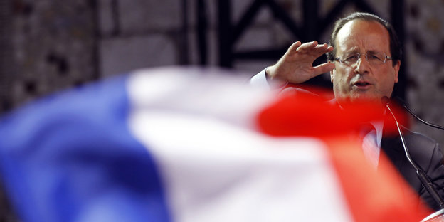 Hollande winkt hinter einer großen französischen Flagge