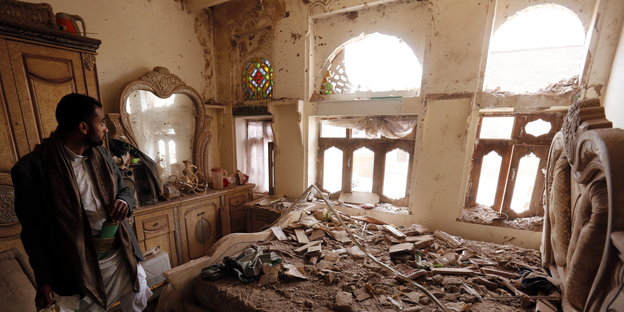 Ein Mann steht im einer zerstörten Zimmer im Jemen