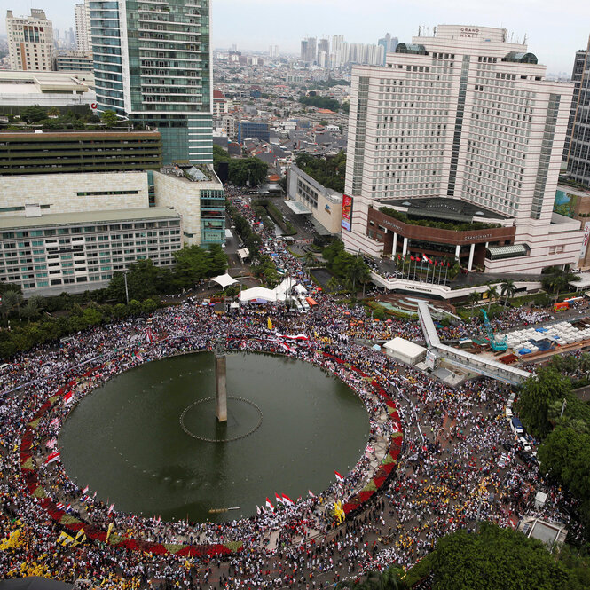 Tausende Demonstranten laufen um einen Kreisverkehr in Jakarta