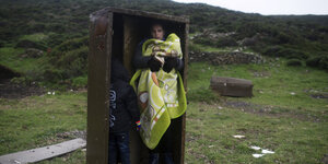 Eine Frau und ein Kind stehen in einem offenen Schrank, der mitten auf einer grünen Wiese steht