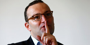 Porträt Jens Spahn. Er hält sich den Finger an den Mund.