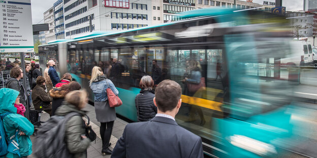Menschen steigen an einer Haltestelle in einen Bus ein