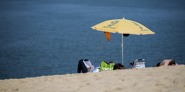 ein Strand mit Gästen und Sonnenschirm