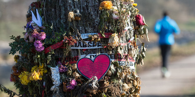 Blumen und Trauerschmuck an einem Baum befestigt
