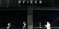 Drei Menschen eilen am Pfizer-Hauptgebäude ín New York vorbei