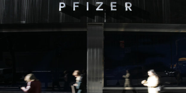 Drei Menschen eilen am Pfizer-Hauptgebäude ín New York vorbei
