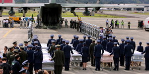Soldaten und Polizisten begleiten die Särge zu einem Transportflugzeug.