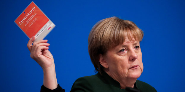 Angela Merkel hält eine rote Stimmkarte in die Höhe