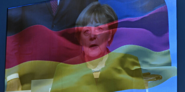 Merkel und eine Deutschlandfahne auf einem Bildschirm