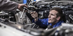 Ein Automechaniker guckt durch Autobauteile