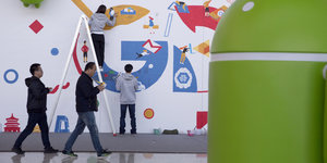 Menschen malen ein Google-Logo an die Wand