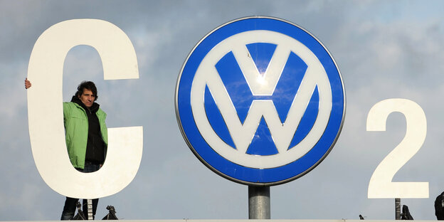 Aktivist hält ein großes weißes C, das zusammen mit dem VW-Logo und einer 2 den Schriftzug "CO2" ergibt