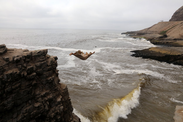 Ein Mann springt von einer Klippe ins Meer