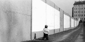 Kind geht an Berliner Mauer entlang
