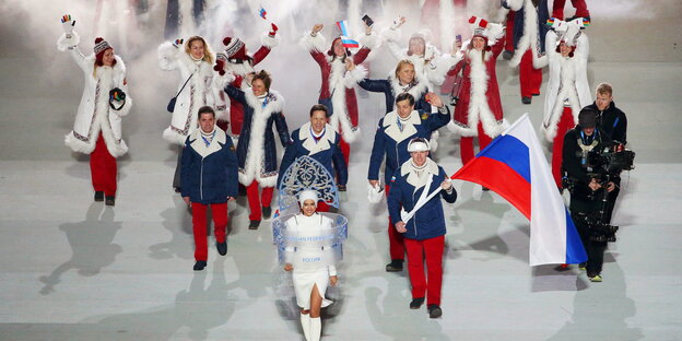 Sportler und Sportlerinnen laufen mit der russischen Flagge in ein Stadion