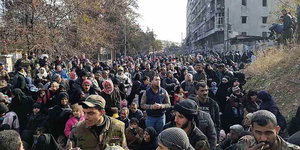 Ganz viele Menschen . versammelt vor zerstörten Gebäuden in Aleppo