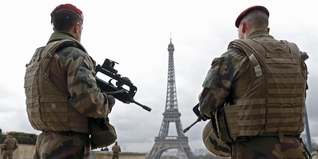 zwei Soldaten mit Waffen im Anschlag vor dem Eiffelturm