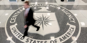 Auf den Boden eingelassenes Wappen der CIA, ein Mann läuft darüber