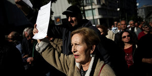 Menschen auf der Straße, eine Frau hält ein Blatt Papier in die Luft