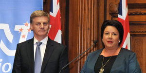 ein Mann und eine Frau stehen jeweils vor einer neuseeländischen Fahne