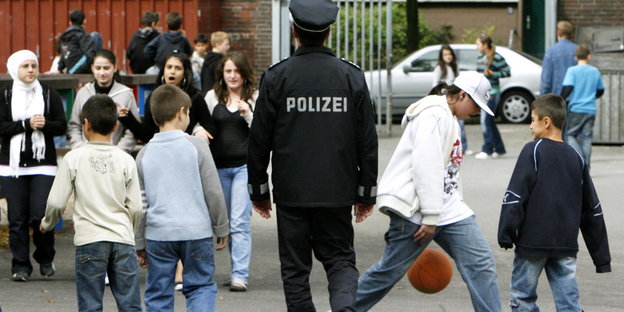 Ein Polizist geht über einen Schulhof