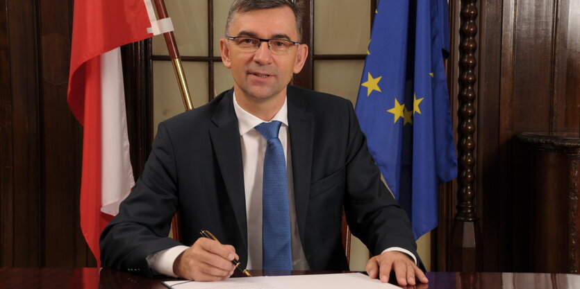 Der polnische Botschafter sitzt vor einer polnischen und einer EU-Flagge