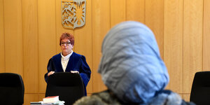 Eine Frau mit Kopftuch sitzt vor einer Richterin im Gerichtssaal