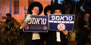 Zwei junge Männer mit Hüten halten Schilder auf denen der Name Trum auf Hebräisch steht