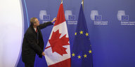 Ein EU-Mitarbeiter zupft die kanadische Flagge neben der EU-Flagge zurecht