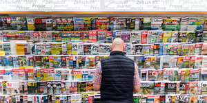 Ein Mann steht vor einem Zeitschriftenregal