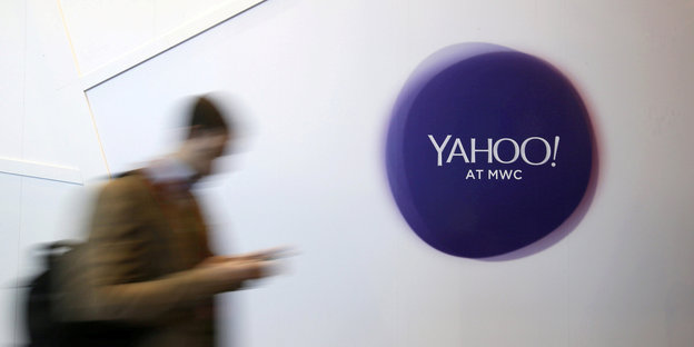 Ein Handynutzer geht an einem Yahoo-Logo vorbei