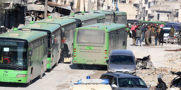 Mehrere Busse stehen in einer Trümmerlandschaft