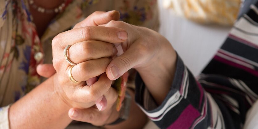 Eine Therapeutin hält in einem Hospiz die Hand einer todkranken Bewohnerin