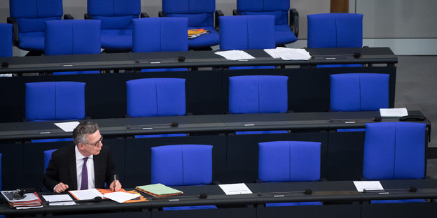 Bundesinnenminister Thomas de Maizière sitzt im Bundestag um ihn herum sind leere Sitze zu sehen